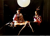 Close-up of the framed surreal photographic artwork showing two women and a nude mannequin under a paper lantern light.
