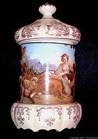 Photo showing side view of musical jewelry box with a woman seated and sheep in the pastoral scene, ornamental top and bottom edges.