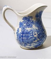 Front and side view of the Royal Staffordshire cream pitcher in Tonquin pattern showing blue and white transferware design with floral and scenic motifs.