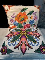 Photo showing two vintage Ukrainian pillows with embroidered floral and geometric patterns on cream backgrounds.