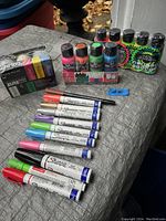 Overview of the Sharpie permanent and paint markers, and acrylic paint bottles on outdoor surface