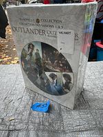 Packaging box of Outlander DVD collection seasons 1-5, showing front and side with stickers, sealed in original shrink wrap.