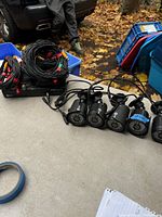 Six black bullet security cameras with IR LEDs and attached long cables shown on a table outdoors with fallen leaves in background