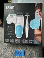 Photo of Braun Silk-épil 5 kit in original box showing epilator, shaver, trimmer, bikini styler, and batteries included.