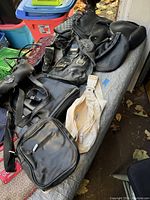 Overview photo showing multiple black leather and fabric vintage purses laid out on a gray surface with fall leaves around.