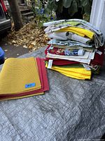 Stack of folded tea-towels and hand towels in various colors and patterns, including white, yellow, red, and patterned designs.