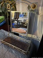 Full view of the vintage metal framed wall mirror with attached shelf showing the frame, mirror, and shelf details.
