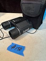 Small black Bushnell binoculars with attached neck strap and black zippered carrying case with logo.