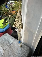 Wind chime triangular top and hanging elements set against a window and plants