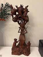 Full view of the wooden carved sculpture showing the princess figure, kneeling figure and floral canopy.