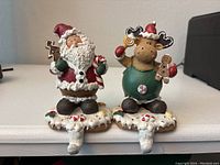 Photo of Santa and reindeer resin Christmas stocking holders on white base with candy decor