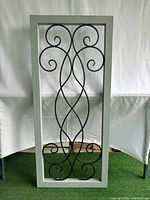 Full view of rectangular wall art with black metal scrolls mounted on light gray wood frame against white backdrop.