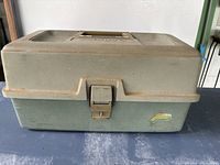 Closed fishing tackle box showing latch and handle with Plano branding on top.