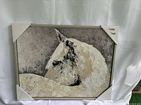 Full view of the canvas painting showing the white horse profile on textured background, framed in wood with corner protectors.