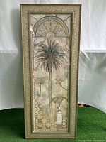 Front view of large decorative framed picture featuring a palm tree and ornamented arch detailing.
