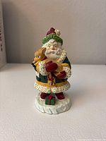 Front view of Lenox Treasure Santa resin figure holding a deer with a small wrapped gift on snow base