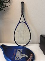 Front view of the Pro Kennex tennis racket with included blue cover displaying brand name and model.