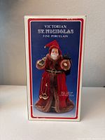 Box front showing the Victorian St. Nicholas figure in red robe with fur trim, labeled as fine porcelain and indicating it can be used as tree top or table piece.