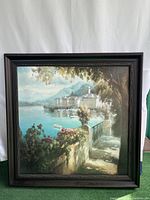 Front view of scenic Italy town and sea canvas painting mounted on a decorative wooden frame.