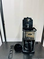 Coffee maker with the top lid open, showing the filter basket and removable parts.