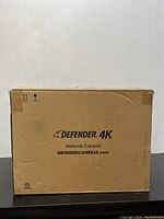 Closed cardboard shipping box with Defender 4K branding and website printed, indicating origin from Welland, Canada.