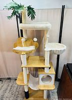 Front view of the cat tower showing the top perch with plush padding, middle hammock, condos, and sisal-wrapped scratching posts.
