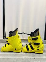 Side view of both yellow Salomon Sport vintage alpine ski boots side by side showing condition and design