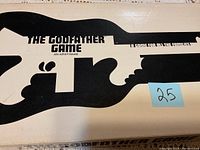 Photo of The Godfather Game 1971 box top showing gun silhouette graphic and game title.