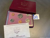 Full view of 1990 uncirculated bank set showing coins in pink felt presentation case, along with maroon outer box and information card.