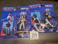 Two Starting Lineup baseball figures in original packaging: Cal Ripken Jr. and Jose Canseco, with 1998 edition labeling.