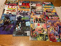 Top-down photo of 25 comic books arranged on a table displaying a variety of titles and cover artwork.