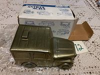 Front-side view of the antique truck coin bank with original box in the background.