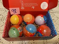 Six Two Sisters Spa Bubble Bombs in a red box, assorted colors and wrapped individually.