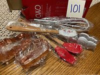 Full view of 8-piece holiday bake set including mini utensils with wooden handles and red silicone tips and three copper metal cookie cutters individually wrapped.