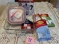 Photo showing kitchen-related items including a 3-cup espresso maker box, two plastic storage containers, a glass baking dish, and Command brand hanging strips and plastic hook.
