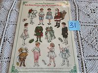 Photo showing the full cut-out sheet with embossed Christmas paper doll characters, featuring children in various holiday costumes.