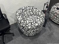 Side view of one swivel chair showing black and white abstract line pattern upholstery, rounded back, and seat
