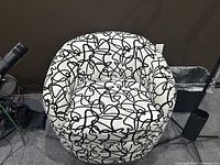 Front view of a barrel-back swivel chair showing white upholstery with black scribble pattern