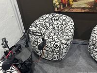 Image showing one swivel chair with white and black abstract pattern upholstery beside a podcast microphone setup.