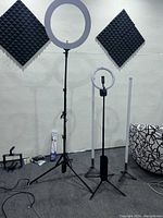 Two rechargeable ring lamps on adjustable tripod stands, two additional vertical lamp stands, set against a wall with soundproof foam panels.