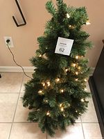Full view of artificial Christmas tree with illuminated white lights and green foliage.