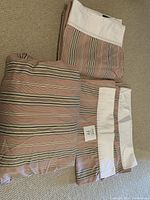 King size striped sheet set folded and placed on carpet, showing pillowcases, flat sheet, and fitted sheet.