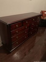 Full view of the dark wood chest of drawers showing the polished finish and drawer arrangement.
