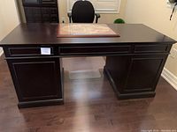 Front view of dark brown desk on hardwood floor