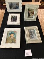 Five small framed art prints displayed on black fabric, showing variety of classic art styles and distressed white frames.