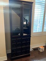 Front view of the dark wood two-section bookcase showing squared panel doors on lower section and glass doors on top section with knobs