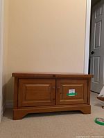 Front view of the pine wood bench showing two paneled doors with round knobs, natural finish, and solid wood base.