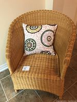 Front view of light tan rattan wicker chair with square patterned cushion on seat.