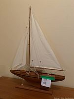 Full view of the tabletop wooden sailboat showing fabric sails and wood base