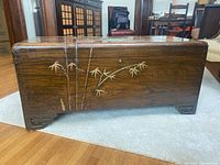 Front view of wooden blanket trunk showing carved bamboo design